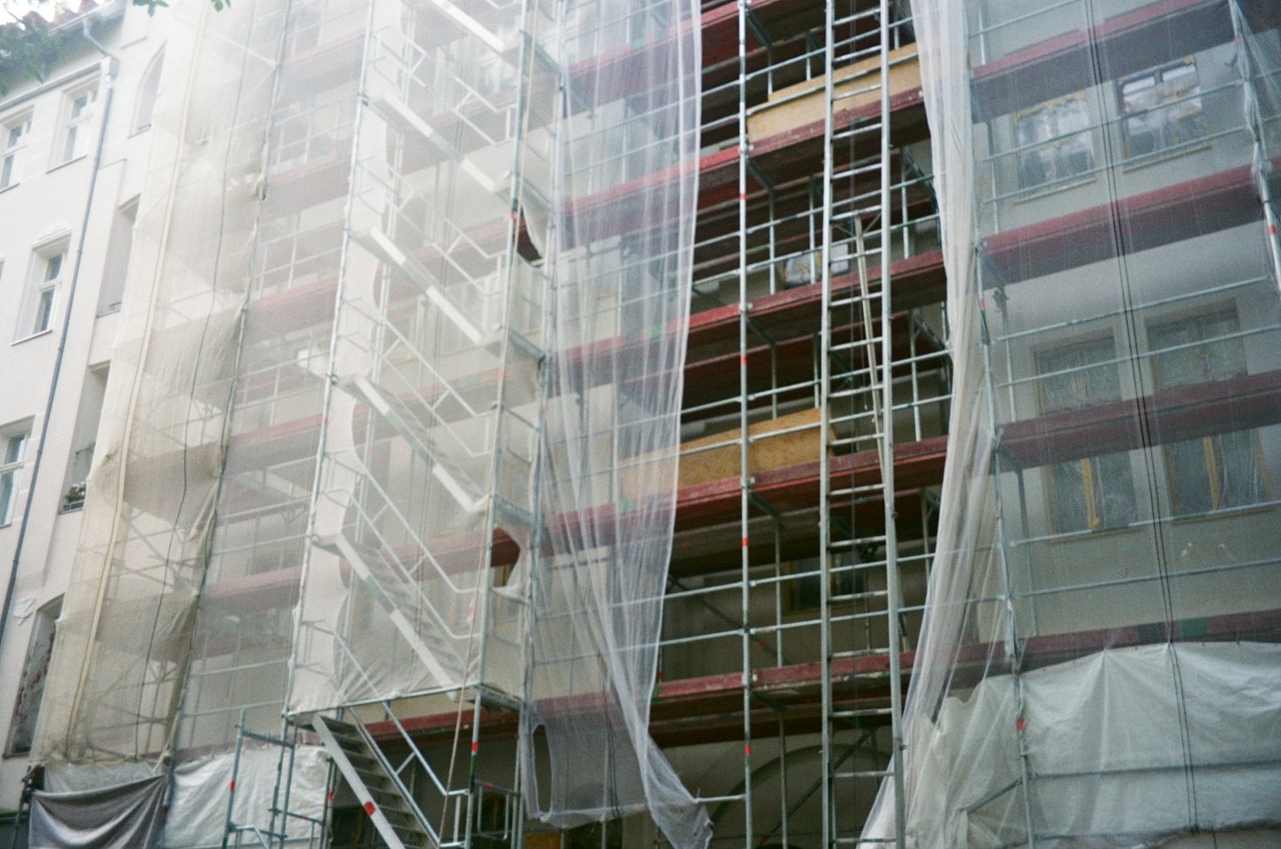 Multi-story residential building covered in complex metal construction scaffolding.