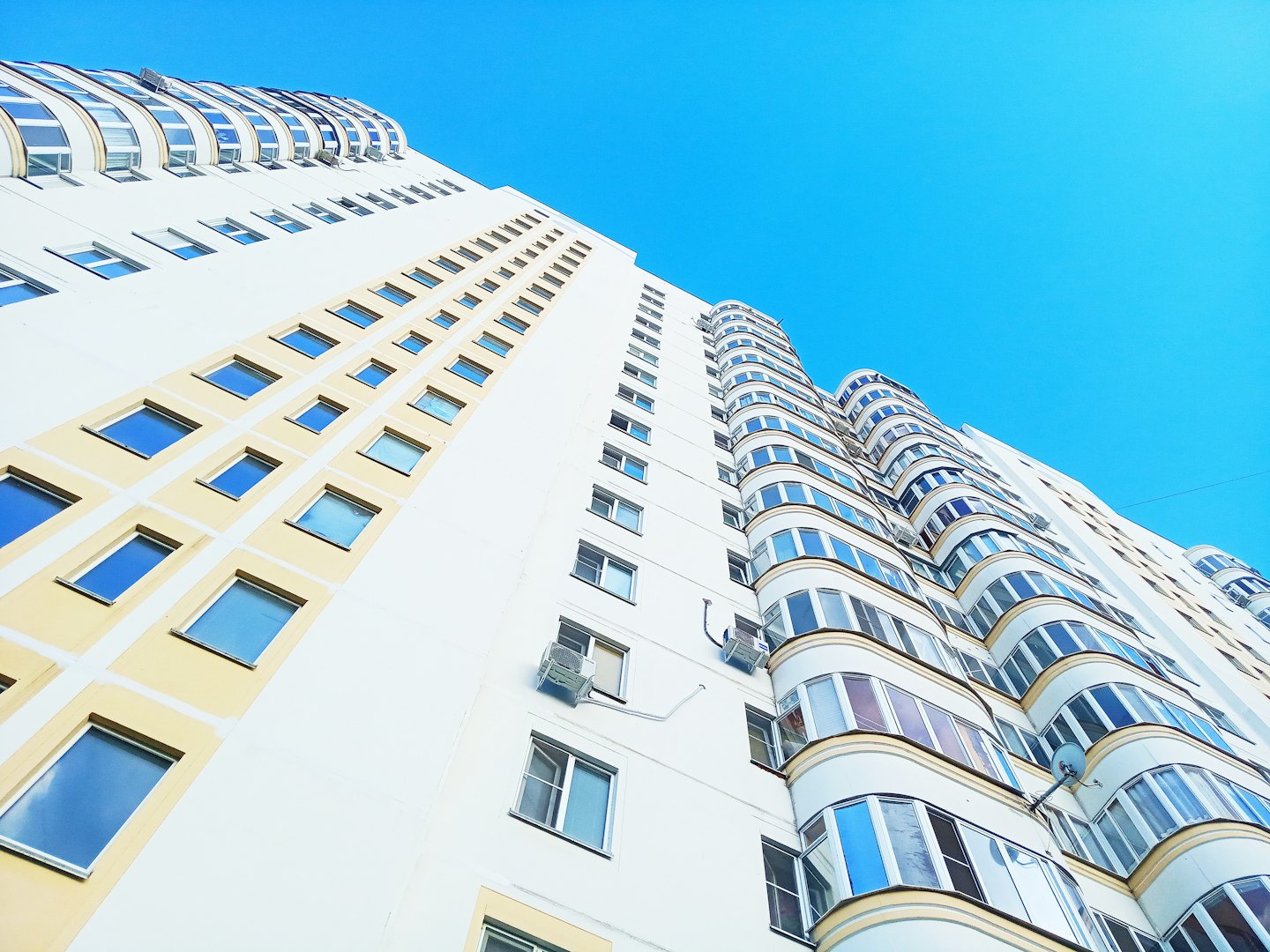Modern residential building with yellow window frames reaching toward the sky.